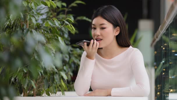 Aziatisch koreaans bedrijf vrouw meisje opnemen spraakherkenning bericht op luidspreker dame vrouw in cafe met behulp van virtuele assistent app herinnering aan de telefoon zitten aan tafel gebruik digitale mobiele bijstand — Stockvideo
