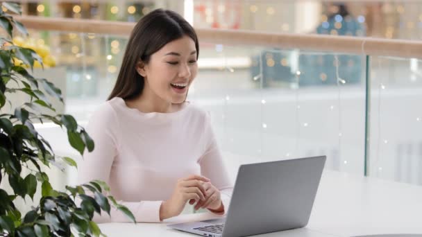 Mujer asiática estudiante chica freelancer hablando con su familia amigo utilizando ordenador portátil que tiene video llamada conferencia remota llamada a distancia en webcam virtual chat en línea sentado en la mesa en la cafetería — Vídeo de stock