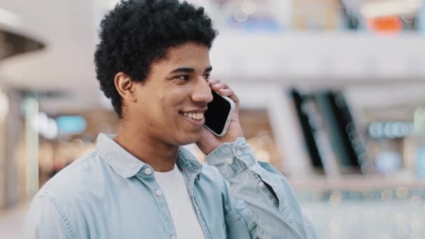 Primer plano chico africano mirando el teléfono móvil respondiendo a una llamada inesperada hablando con su novia familia sonriendo chateando en el teléfono celular charla amigable a distancia conexión celular utilizando la aplicación de teléfono inteligente — Vídeos de Stock