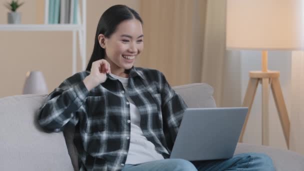 Asiática sonriente mujer de negocios freelance estudiante en línea profesora psicóloga mujer sentada en el sofá en casa remoto hablando video llamada conferencia aplicación chat hablando en webcam saludando consulta — Vídeos de Stock