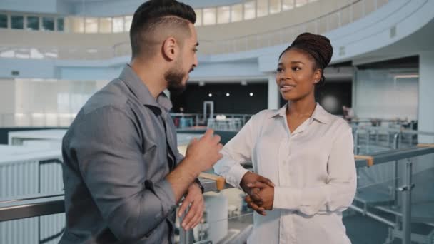 Partner commerciali multietnici amichevoli colleghi donna africana e uomo arabo indiano che parlano in piedi nella moderna sala dell'ufficio aziendale due dipendenti diversi che hanno una discussione aziendale durante la pausa di lavoro — Video Stock