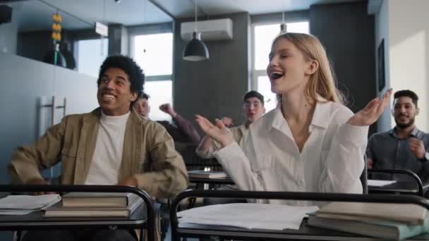 Grupo diverso jovens estudantes colegas de trabalho sentados em sala de aula ouvindo palestra entusiasmado se alegrando na vitória celebrando o sucesso comum aprendendo boas notícias ganhando agitado gritando de vitória — Vídeo de Stock