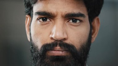 Sinirli Arap iş adamının yakın plan portresi sakallı, Latin sakallı bir erkek kameraya kendinden emin bir şekilde bakıyor. Acımasız bakışları umutsuzluğu gösteriyor. Mutsuz bir yüz ifadesi.