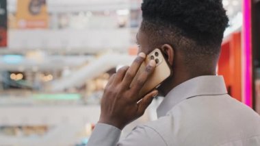 Arka planda genç Afro-Amerikan iş adamının cep telefonuyla konuşması iş görüşmelerine cevap vermesi müşteri danışmanına telefonla arkadaşlarıyla iletişim kurmasını tavsiye etmesi.