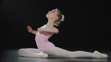 Genç kız çocuk jimnastikçi dans sınıfı atletik bayan esneme hareketleri yapıyor spor salonunda esnek dansçı balerin içeride salonda ritmik jimnastik yapıyor.