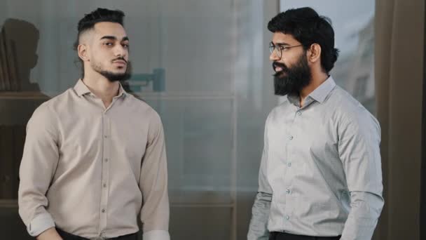 Dos amigos hombres multirraciales diversos colegas socios de negocios hombre hispano árabe barbudo tipo de pie en la oficina posando con los brazos cruzados asintiendo de acuerdo cabeza mirando cámara confidente compañeros de trabajo — Vídeos de Stock