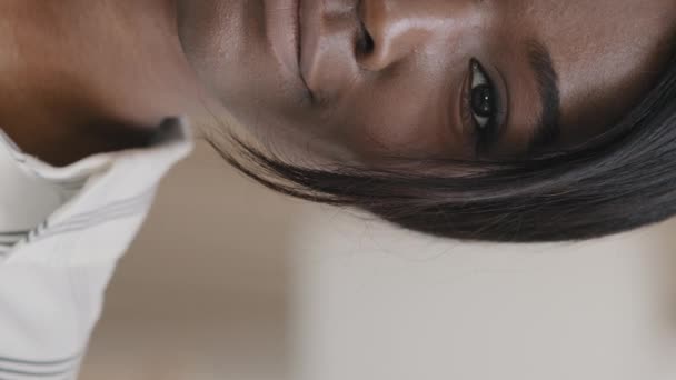 Κάθετη άποψη headshot μισό ανθρώπινο γυναικείο πρόσωπο με σκούρα μάτια ευτυχισμένη Αφροαμερικανή γυναίκα χαμογελώντας κοιτάζοντας κάμερα φυσική ομορφιά μακιγιάζ διαφήμιση καλλυντική διαδικασία προώθηση διόρθωση λέιζερ — Αρχείο Βίντεο