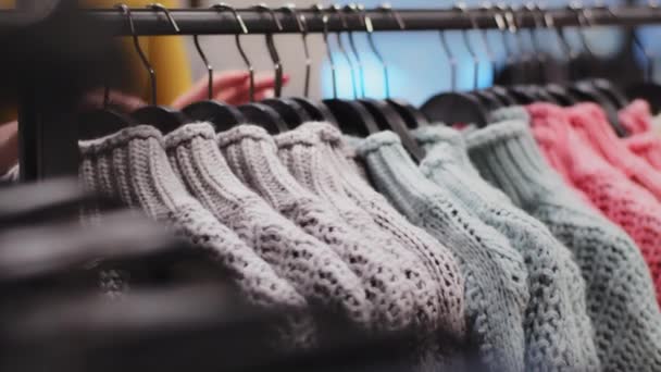 Close-up ruhák vállfa színes pulóverek ruházati üzlet női kéz válogatás ruházat felismerhetetlen nő ügyfél választ ruhát butikban vásárol új dolog vásárlás kedvezmény vásárlás — Stock videók