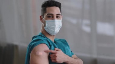 Arap doktor doktor hemşire cerrahi maske takıyor. Küresel aşı sonrası omzundaki bandaj izine bakarak aşı kovid-19 virüs korumasını gösteriyor.