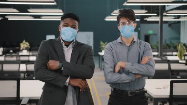 2人のビジネスマンアフリカのアラビア人の同僚ビジネスパートナーの管理者は、ホールオフィスの呼吸保護距離の顔マスクを身に着けている安全に交差腕で立つ19検疫 — ストック動画