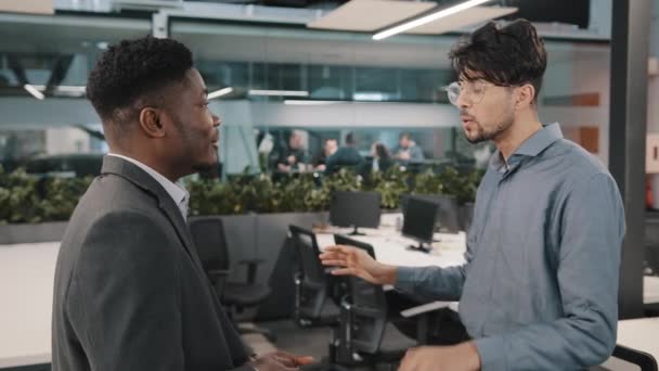 Two multiracial male business colleagues partners african bearded boss man talking with European office employee wearing glasses negotiation accept idea give high five agreement partnership teamwork — ストック動画