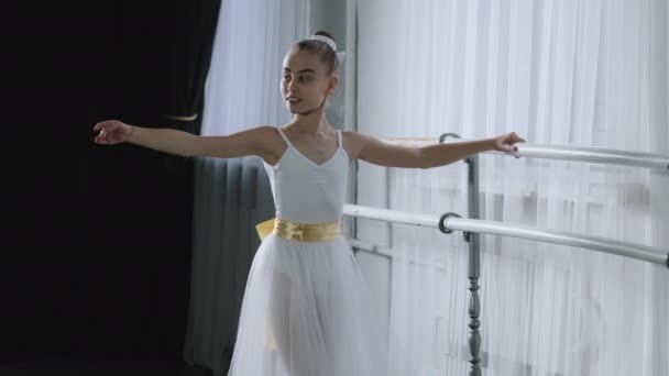 Biały artystyczny elastyczny profesjonalny balerina nastolatek dziewczyna w tutu obok balet barre robi taniec ćwiczenia próby inscenizacja choreografia klasyczne praktyki podnoszenie nogi i ręka w górę wdzięk — Wideo stockowe