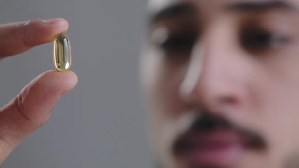 Macro shot duidelijke capsule bij mannelijke arts cardioloog hand zieke man tonen op camera transparante pil vitamine tablet remedie nemen pijnstiller medische drug apotheek medicatie behandeling van dichtbij te bekijken — Stockvideo