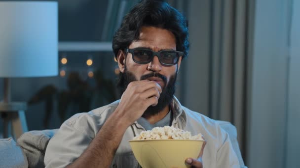 Porträtt arabiska latinamerikansk indian muslim skäggig man i 3D-glasögon titta på TV avslappnad kille i virtuella glasögon njuter av filmprogram på nätet äta krispiga popcorn hemma på kvällen mörk — Stockvideo