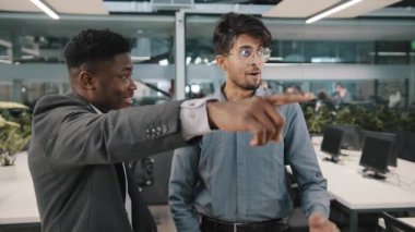 İki iş arkadaşı Afrikalı patron girişimci Arap iş arkadaşına modern lobideki yeni ofis yerini gösteriyor. Şirket güncellemesi sunuyor neşeli arkadaş işaret parmağı sürprizi.