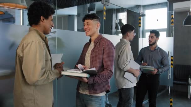 Unga manliga studenter står inomhus kommunicera förbereder examen kaukasiska kvinna student glatt kör ut klass med goda nyheter utmärkta resultat vänner klasskamrater fira seger gratulera flicka — Stockvideo