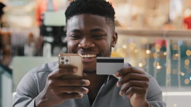 Young happy smiling guy shopper klient sklepu internetowego klient dokonuje zakupu płacąc kartą kredytową za pomocą błyskawicznych płatności mobilnych przy użyciu smartfona kupując zdalnie e-bankowość usługa app bezpieczna płatność — Wideo stockowe