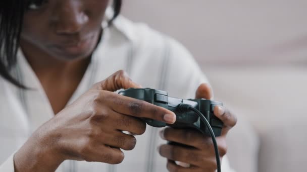 Primer plano manos femeninas joven afroamericana concentrada gamer sosteniendo joystick jugando videojuegos en la consola relajarse en casa solo disfrutando del concepto de entretenimiento juego utilizando tecnología moderna — Vídeo de stock