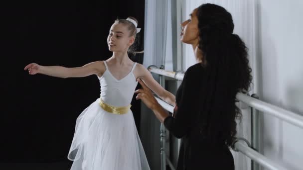 Kaukaski dziewczyna nastolatek student balerina w tutu robi taniec ćwiczenia w pobliżu balet barre słuchanie wyjaśnienia porady od dorosły nauczyciel kobieta trener próby choreografia taniec edukacja — Wideo stockowe