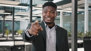 Afrikalı erkek iş adamı, genel müdür, teknoloji şirketinin kendine güveni tam. Neşeli bir duruş sergiliyor. Geliştirme stratejisini, el hareketlerine odaklanarak gülümsüyor.