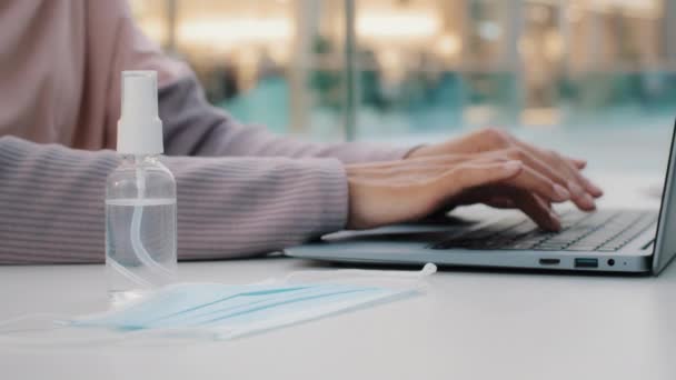 Gros plan mains féminines jeune femme d'affaires méconnaissable tapant sur ordinateur portable observe les précautions pendant la pandémie prend soin de la santé utilisations désinfectant porte masque de protection médicale fonctionne au bureau au bureau — Video