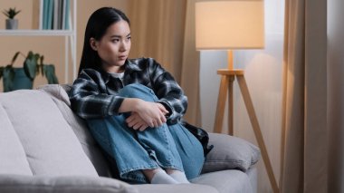 Yalnız başına üzgün, düşünceli Asyalı kadını üzen, hayal kırıklığına uğramış, evde oturup sorunları düşünen, sorunlu, kötü ruh halinde, kalbi kırık, erkek arkadaşı PMS sendromuyla kavga eden bir kız.