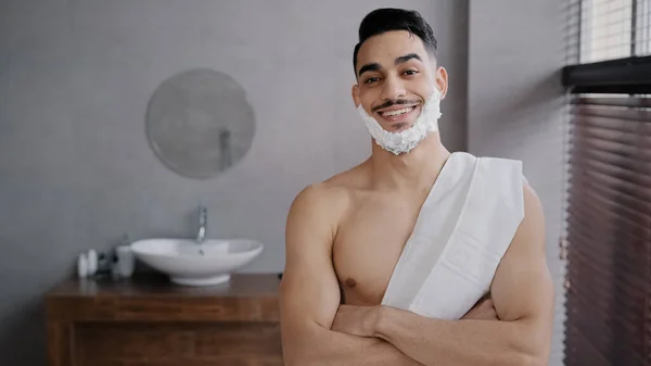 Όμορφος με αυτοπεποίθηση γυμνός Άραβας 30άρης μυώδης άντρας που στέκεται στο μπάνιο στο σπίτι στο ντους του ξενοδοχείου κοιτάζοντας την κάμερα με λευκό αφρό ξυρισμένο τζελ στο πρόσωπο γενειάδας σταυρώνει τα χέρια ποζάροντας έτοιμος για ξύρισμα — Φωτογραφία Αρχείου