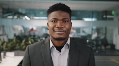 Yakışıklı afro-amerikan çok ırklı girişimci işadamı ofiste dikiliyor profesyonel erkek takım elbiseli patron kameraya bakıp gülümsüyor.