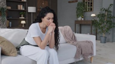 Heyecanlı, stresli, kanepede oturan genç bir kadın üzüntüyle öğrendiği kötü haberlerle sağlık sorunları hakkında endişeleniyor. Kişisel sorunları düşünüyor, depresyondan muzdarip.
