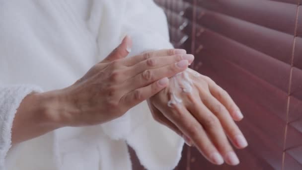 Close-up kobiet ręce nierozpoznawalne młoda zdrowa kobieta w szlafroku stosuje krem nawilżający traktuje skórę z odżywczym nawilżający balsam do suchych ramion robi codzienną rutynową pielęgnację kosmetyczną pielęgnacji skóry — Wideo stockowe