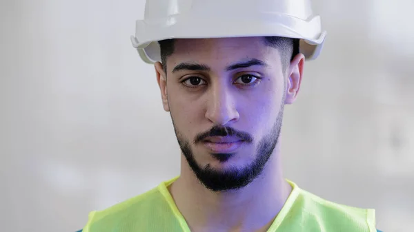 Close-up portrait serious hispanic man contractor mechanic male builder wear special uniform safety helmet looking at camera confident arabian engineer foreman posing with emergency light background —  Fotos de Stock