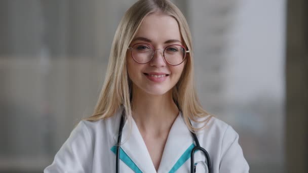 Kobieta pracownik medyczny lekarz kobieta w okularach patrząc na aparat pokazuje kciuki do góry w klinice szpitalnej zaleca szczepienia studentka ubezpieczenia zdrowotnego na uczelni medycznej dobry staż — Wideo stockowe