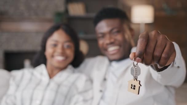 Blurred unfocused view African American married couple newlyweds wife and husband holding keys to new house rented apartment happy with real estate. Girlfriend and boyfriend satisfied living together — ストック動画