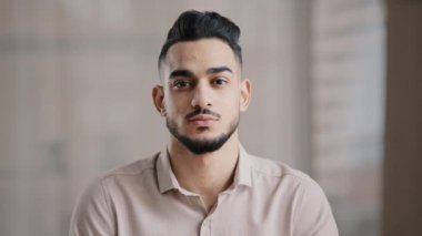 Ciddi bir şekilde portreyi kapat İspanyol genç iş adamı profesyonel işçi düşünceli erkek yüzü kendine güveni olan bir yüz ifadesi ofiste kameraya bakarak düşünme kararı ver.