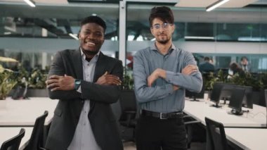 Çok ırklı iş arkadaşları, çeşitli Arap iş arkadaşlarına gülümsüyor. Afrikalı genç yönetici, iş yerindeki kameralara bakarak iç içe geçmiş silah çekiyorlar.
