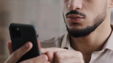 Erkek ellerini kapat genç Latin Arap profesyonel işçi cep telefonu tutuyor sosyal ağlarda sohbet ediyor iş yerindeki internet sörf bilgilerine cep telefonu uygulaması kullanarak mesaj atıyor.