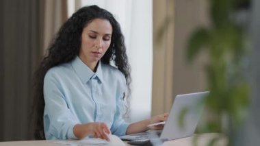 Odaklanmış genç girişimci kadın muhasebeci kağıt notlar tutuyor bilgisayar başvurularında aylık elektronik mali rapor bütçesi yapıyor gelir faturalarını çevrimiçi ödüyor