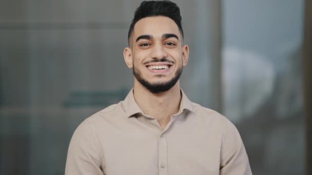 Šťastný mladý muž hispánský pohledný muž se zubatým úsměvem při pohledu na kameru muž tvář portrét podnikatel úsměv arabsky profesionální manažer podnikatel pózování pozitivní v moderní kanceláři zblízka pohled — Stock video
