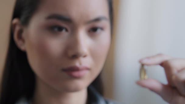 Detailní záběr mladá asijská nemocná dívka pocit nevolnosti držení rybího tuku kapsle vitamín výživný doplněk medikace dávka lék na nemoc analgetika myšlení o lékařské ošetření žena s Omega 3 — Stock video