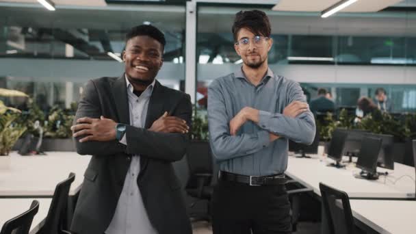 Multiraciale paar collega 's uit het bedrijfsleven glimlachen diverse collega' s Arabisch jongeman Afrikaans manager zakenman man staan binnen samen poseren kruisen armen kijken naar camera op kantoor — Stockvideo