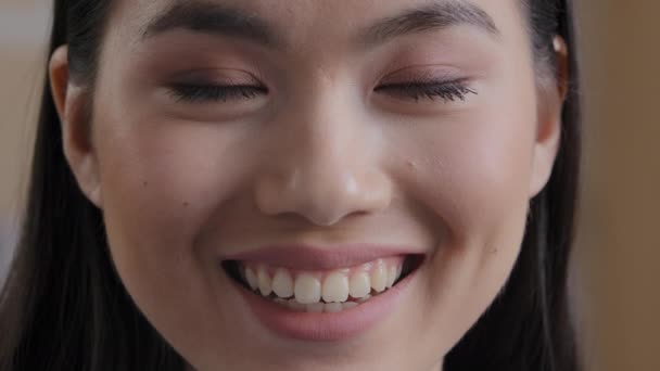 Nahaufnahme Kopfschuss weiblichen Portrait 25s asiatische Ethnizität Frau lächelt weit zahmen Blick in die Kamera. Wunderschöne Koreanerin glücklich zufriedene Dame mit perfekter Gesichtshaut natürliches Make-up weiß Lächeln drinnen — Stockvideo