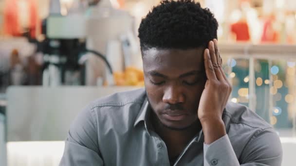 Close-up young unhealthy tired african american man feels headache pressure holding hands on to head suffering from chronic migraine experiencing strong painful feeling unwell worried stress anxiety — стоковое видео