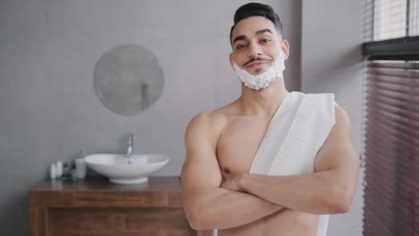 Guapo confiado hombre árabe desnudo 30s macho musculoso de pie en el baño en casa en la ducha del hotel mirando a la cámara con espuma blanca gel de afeitar en la barba cruzando los brazos posando listo para afeitarse — Vídeos de Stock