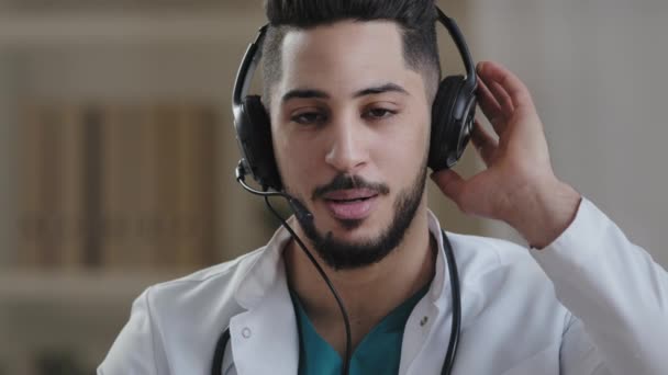 Web camera view young male hispanic doctor practitioner arab man wear headphones with microphone giving online virtual consultation provide remote medical support in virtual chat telemedicine concept — Vídeo de stock