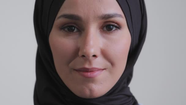 Close-up araber menneskelige kvindelige ansigt islam kvinde med naturlig makeup klar hud attraktiv temmelig muslimsk pige iført traditionelle hijab tørklæde stående indendørs foran ser på kameraet selvsikker syn – Stock-video