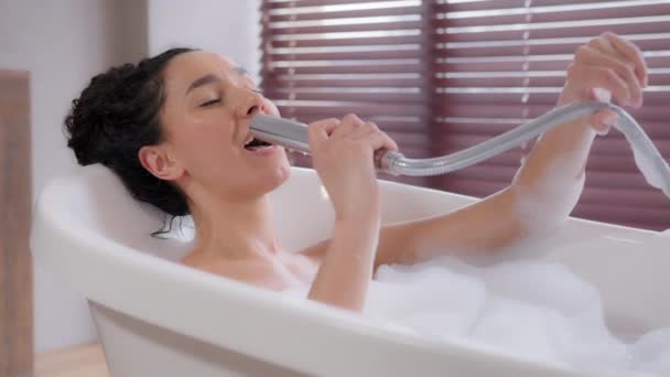 Young funny happy indian naked woman takes foam bath relaxes in bathroom emotionally sings favorite song in shower like microphone enjoys dynamic music having fun morning daily hygiene body skincare — Vídeos de Stock