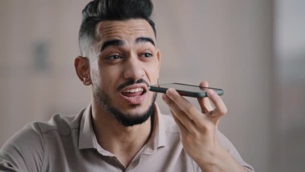 Arabian millennial affärsman entreprenör sitter på arbetsplatsen prata på högtalartelefon med vän gör röstigenkänning använda virtuell assistent digital ansökan spela in ljudmeddelande på mobilappen — Stockvideo