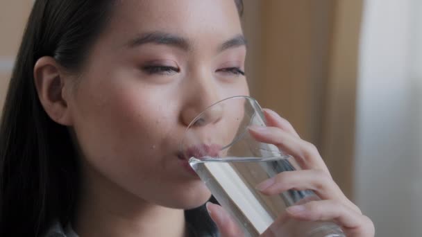 Close up mulher asiática beber água limpa entrega em casa segurando vidro almoço manhã ritual diário bom hábito menina sente sede cuidados de saúde hidratação desidratação refresco bebida sorrindo sentindo-se bem — Vídeo de Stock