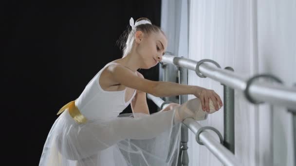 Nastolatek kaukaski balerina dziewczyna nastolatek tancerz dziecko student w taniec sala robi choreograficzne ćwiczenia w szkoła tańca w pobliżu baletu barre rozciąganie uczucie nogi ból kolano kontuzja rozciągnąć problem — Wideo stockowe