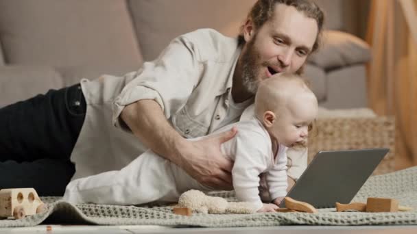 Voksen kaukasiske far skægget enlig far med nyfødt baby gør videoopkald til mor eller slægtninge indendørs far med spædbarn baby vinke hænder hilsen taler online konference fjern chat – Stock-video